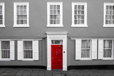 A facade of a traditional village house in Great Britain. Its red door are isolated in a black and white picture. 