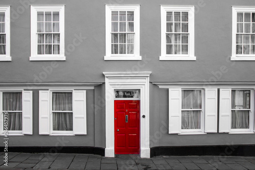 Fasada tradycyjnego wiejskiego domu w Wielkiej Brytanii. Jej czerwone drzwi są odizolowane na czarno-białym zdjęciu.