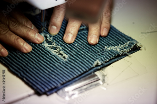 Romans hands sewing denim on sewing machine