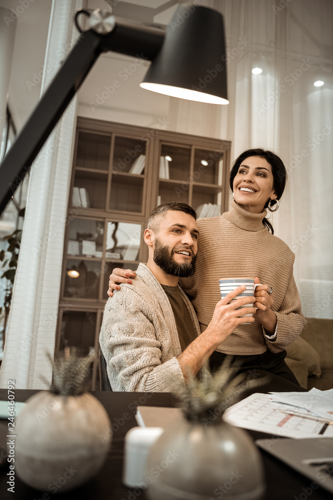 Attractive dark-haired woman with wide smile chilling on knees of her man Attractive dark-haired woman with wide smile chilling on knees of her man