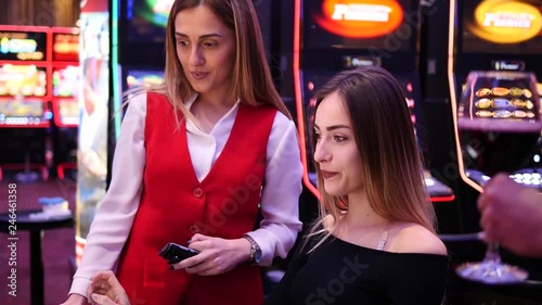 Dealer in Casino helps girl play on slot machine. Girl won at the Casino.
