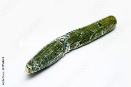 A picture of a rotten cucumber packed in the plastic foil. The foil is useless, it only damages the vegetable and it only goes mouldy. Isolated on a white background.
