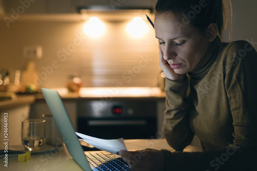 Serious woman reading her financial bills at home
