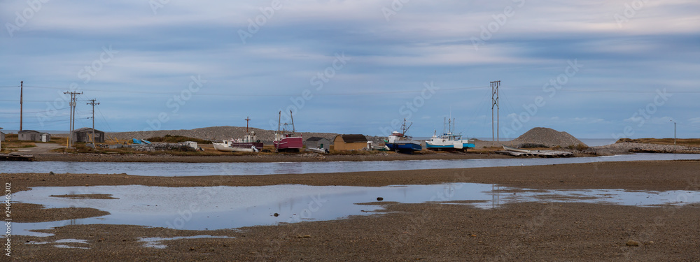 Panoramic view of small fishing boats sitting on a shore during a cloudy day. Taken in Parson's Pond, Newfoundland, Canada. Panoramic view of small fishing boats sitting on a shore during a cloudy day. Taken in Parson's Pond, Newfoundland, Canada.