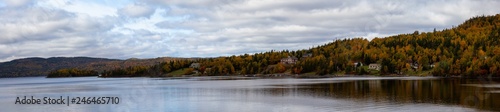 Beautiful panoramic landscape view of residential homes by the lake during a cloudy day. Taken at Georges Lake, Newfoundland, Canada.