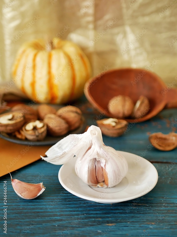 Garlic, walnuts, vegetables on a wooden table, ingredients for preparing healthy food, seasonal, organic, vegetarian cuisine Garlic, walnuts, vegetables on a wooden table, ingredients for preparing healthy food, seasonal, organic, vegetarian cuisine