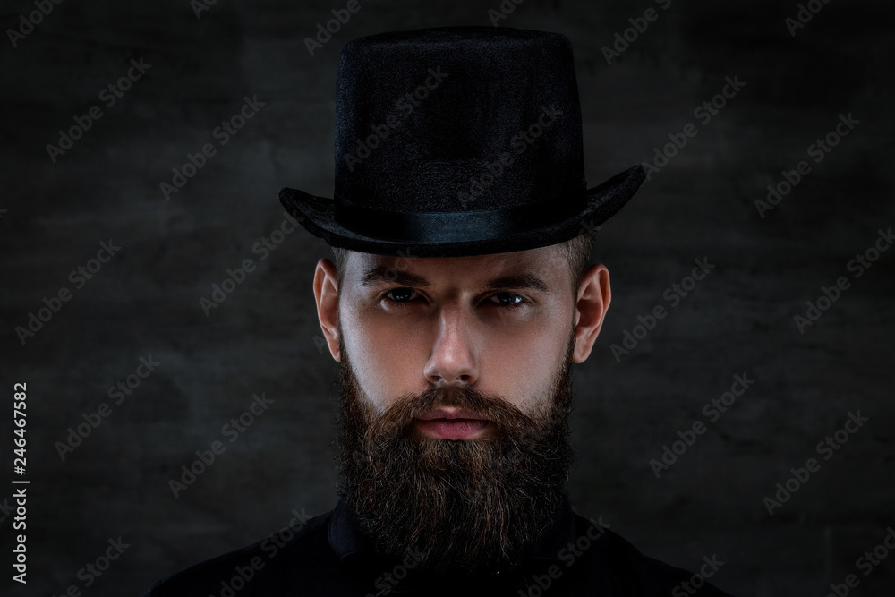 A serious old-fashioned bearded man wearing a top hat, looking at a camera A serious old-fashioned bearded man wearing a top hat, looking at a camera