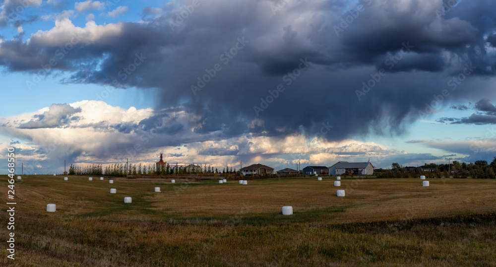 Panoramic view of farm fields with Hay Bales during a cloudy and stormy evening. Taken West of Winnipeg, Manitoba, Canada. Panoramic view of farm fields with Hay Bales during a cloudy and stormy evening. Taken West of Winnipeg, Manitoba, Canada.