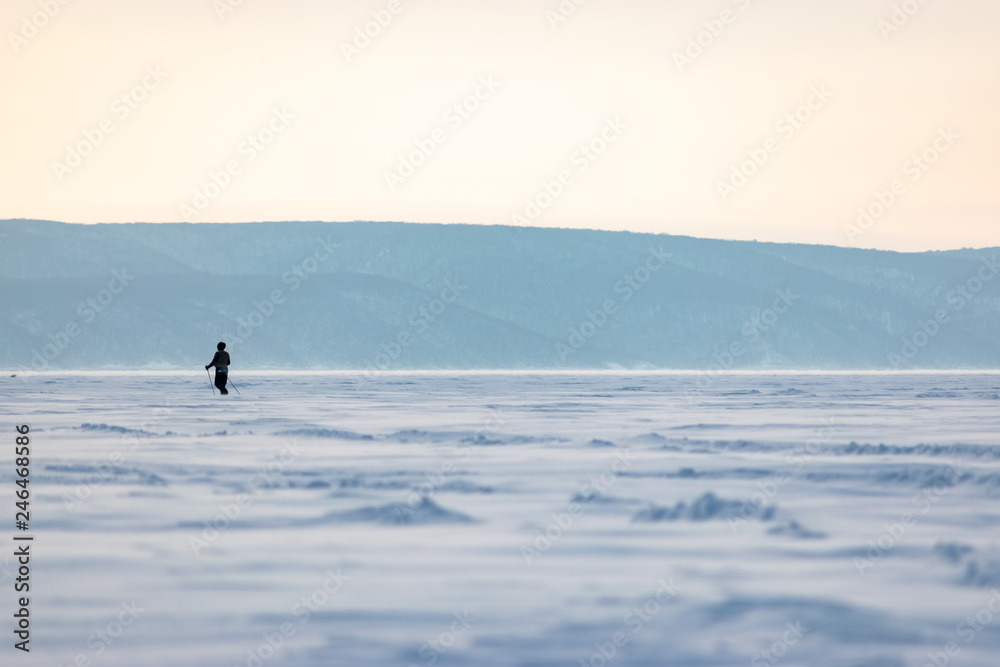 Man crossing winter landscape on a background of mountains