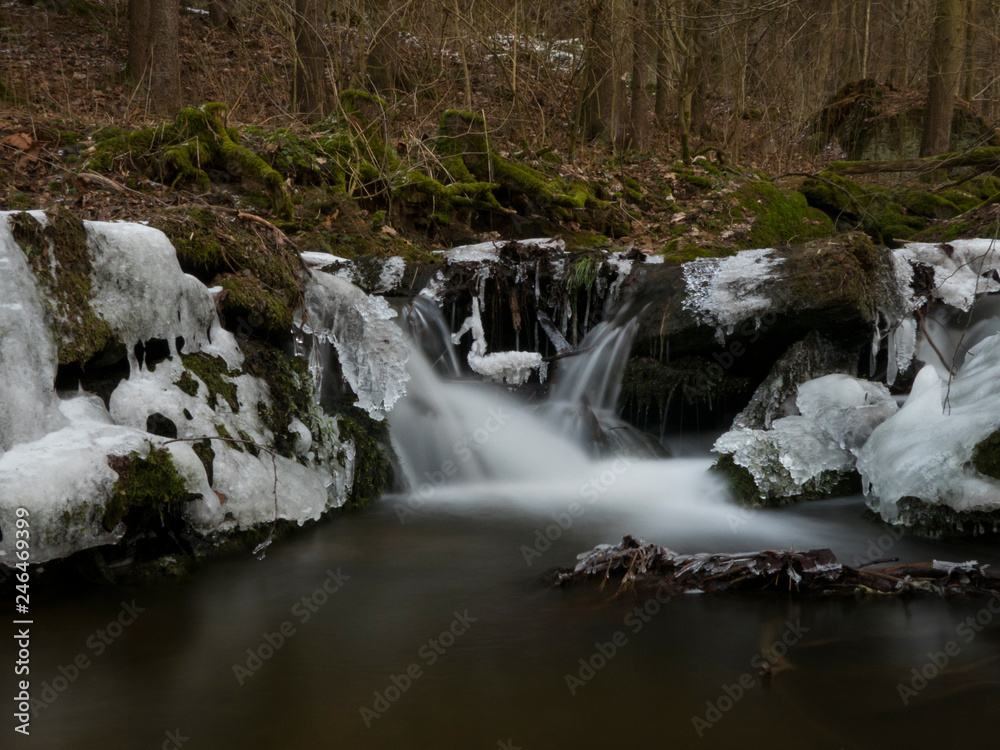 smooth motion of wild water in a river in winter with snow and ice on rocks and stones in the beautiful nature of a forest smooth motion of wild water in a river in winter with snow and ice on rocks and stones in the beautiful nature of a forest