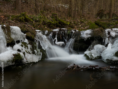 Fototapeta Naklejka Na Ścianę i Meble -  smooth motion of wild water in a river in winter with snow and ice on rocks and stones in the beautiful nature of a forest