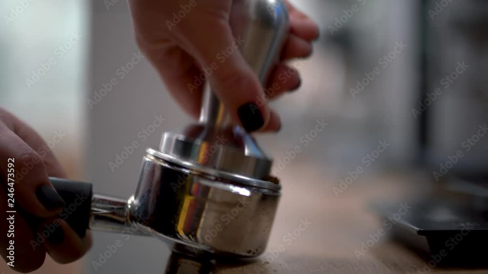 Woman or barista presses the ground coffee in the holder to make a delicious coffee and going to switch on coffee machine Woman or barista presses the ground coffee in the holder to make a delicious coffee and going to switch on coffee machine