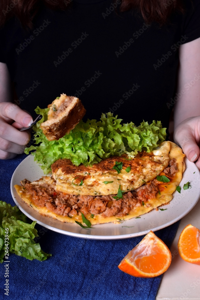 Woman is eating a piece of omelette with a fork. Breakfast meal