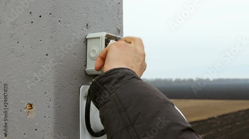 An electrician man repairs installs a video surveillance system.
