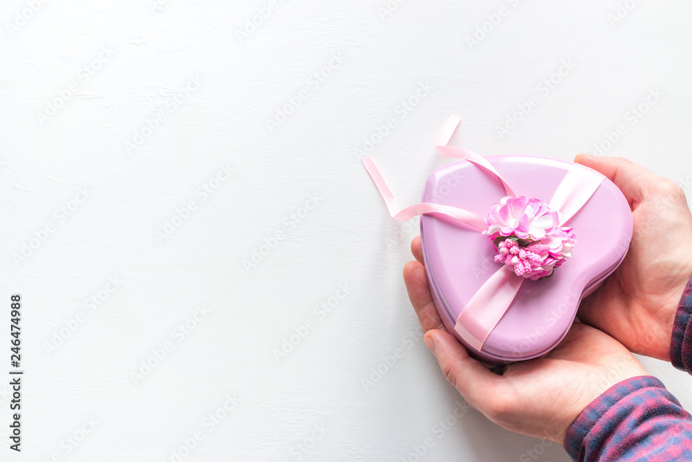 man gives a gift in the shape of a heart for Valentine's Day on a white background with space for text man gives a gift in the shape of a heart for Valentine's Day on a white background with space for text