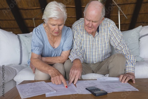 Senior couple discussing over medical bills in living room