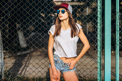 Pretty sporty brunette girl near metal grid on playground. photo