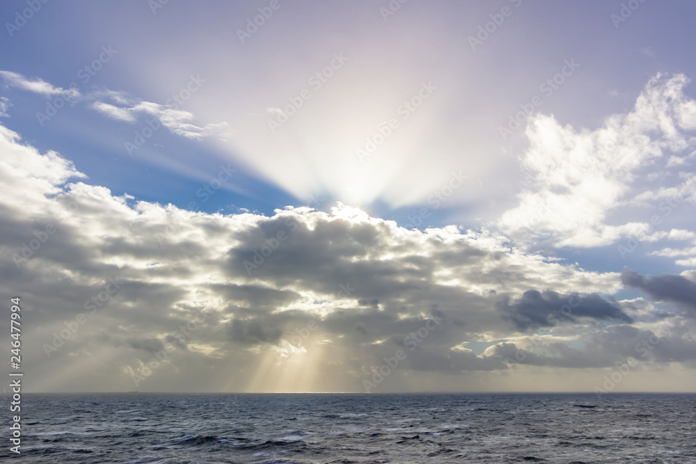 Obraz premium The clouds above the sky creating an amazing view of lines and formations trying to close the sun rays that scape from the clouds creating a moody sky with the rays of light illuminating the scene