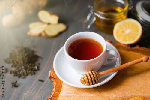 Cup of tea with lemon, ginger, honey and honey stick on wooden rustic table .