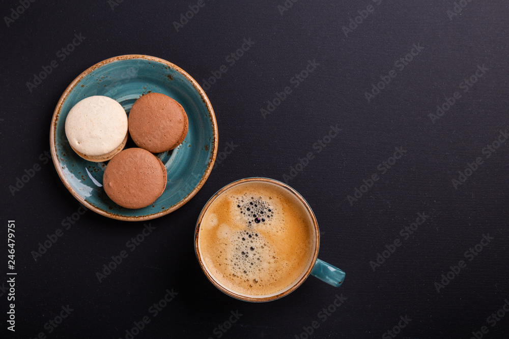 Blue cup of coffee and macaroons on the dark wooden table. Coffe break. Top view. Flat lay Blue cup of coffee and macaroons on the dark wooden table. Coffe break. Top view. Flat lay