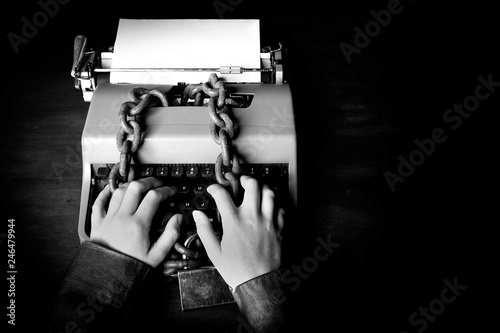 Fotografía Information censorship - Hands writing on a typewriter locked with a chain