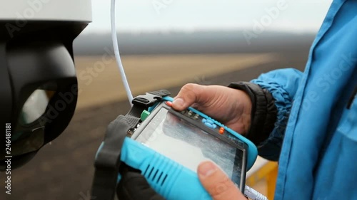 An electrician man repairs installs a video surveillance system. Using PC tester