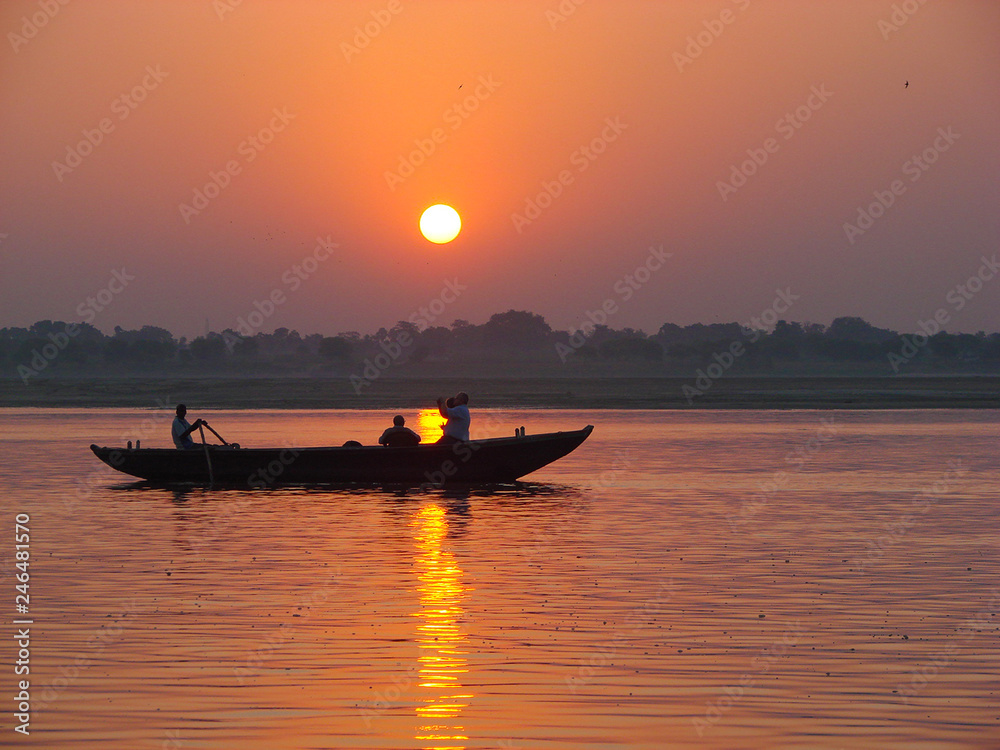 Pilgrims floating by boat of the sacred Ganges river. Sunrise in Varanasi, Uttar Pradesh, India.