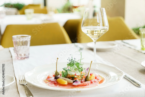 tuna carpaccio and white wine on the table in the restaurant