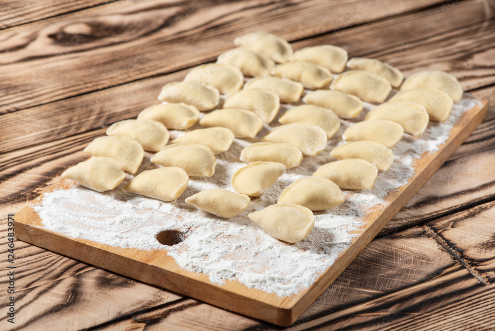 Raw dumplings on wooden cutting board, is ready to boil. Also known as Vareniks. Ukrainian traditional cuisine