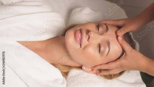 Calm beautiful fair-haired woman getting facial massage, medicine treatment. Reducing stress, weekend, holiday