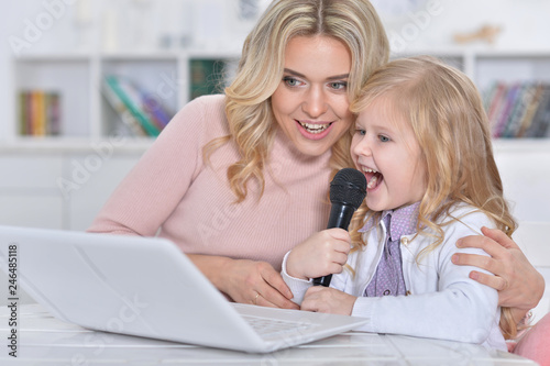 Portrait of young woman with girl using laptop and singing karaoke