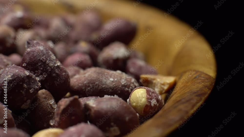 Raw unpeeled peanuts fried with salt. Rotation. Snack closeup. Peanuts in a bowl. Selective focus. black background. Studio shot. Healthy food concept. Raw unpeeled peanuts fried with salt. Rotation. Snack closeup. Peanuts in a bowl. Selective focus. black background. Studio shot. Healthy food concept.