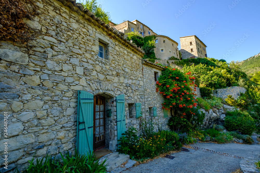 Rue et façades des maisons de village de Brantes, Provence, France. Fleurs de trompette de Virginie (Campsis radicans).