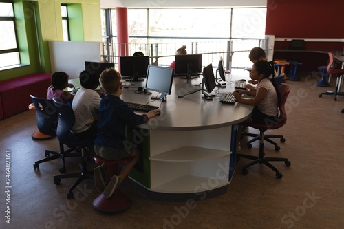 Group of schoolkids studying on desktop pc in school