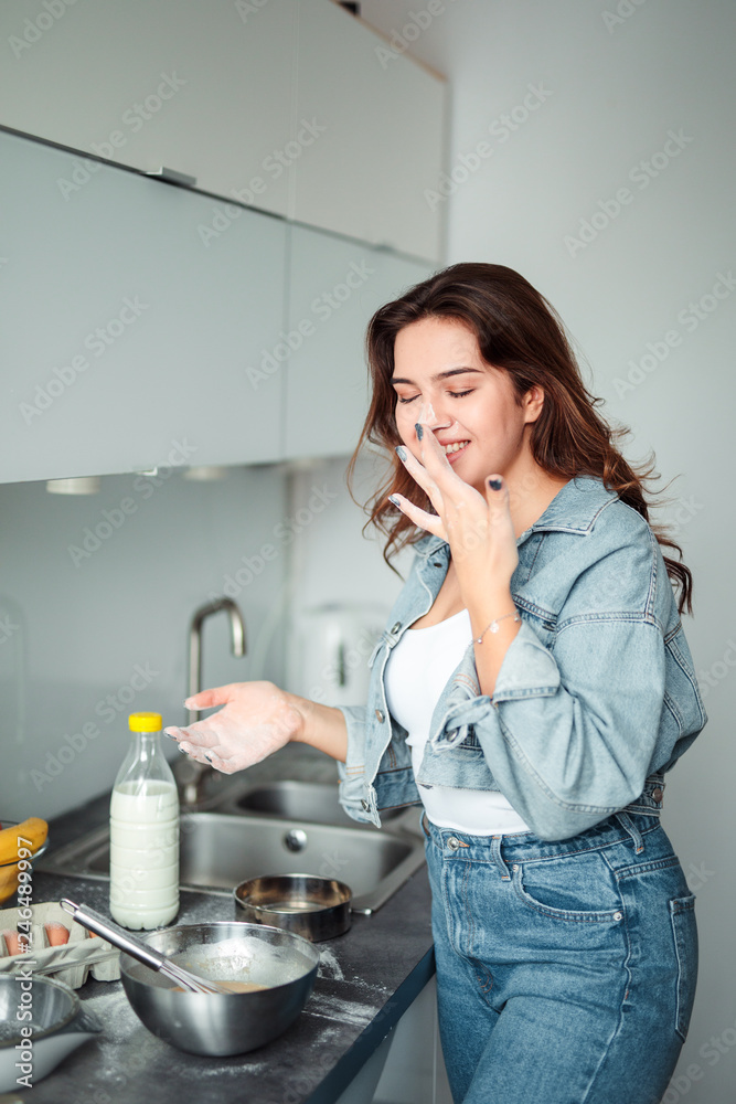 Girl cooking pancakes in the kitchen, home with flowers, eggs, fruits on the table. Girl cooking pancakes in the kitchen, home with flowers, eggs, fruits on the table.