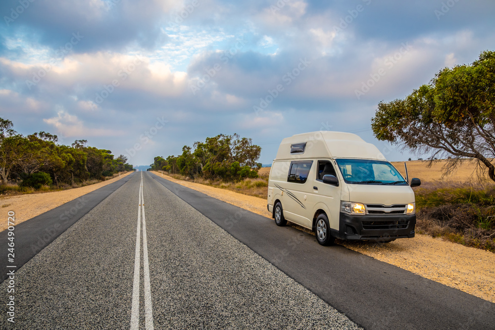 Campervan in Australia standing at the site of straight, endless road in late afternoon Campervan in Australia standing at the site of straight, endless road in late afternoon