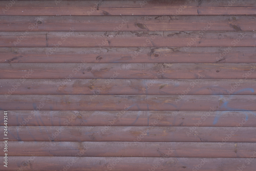 Wooden wall painted with brown paint with traces of blue paint from a can. The texture of the wooden wall.