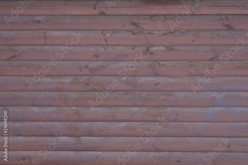 Wooden wall painted with brown paint with traces of blue paint from a can. The texture of the wooden wall.