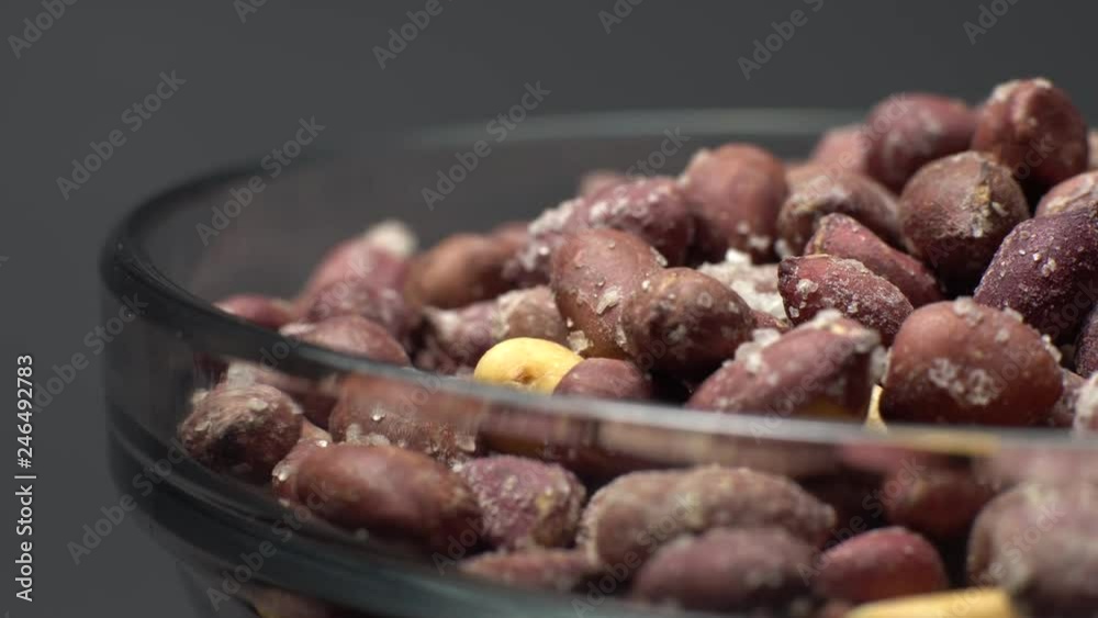 Raw unpeeled peanuts fried with salt. Rotation. Snack closeup. Peanuts in a bowl. Selective focus. grey background. Studio shot. Healthy food concept. Raw unpeeled peanuts fried with salt. Rotation. Snack closeup. Peanuts in a bowl. Selective focus. grey background. Studio shot. Healthy food concept.