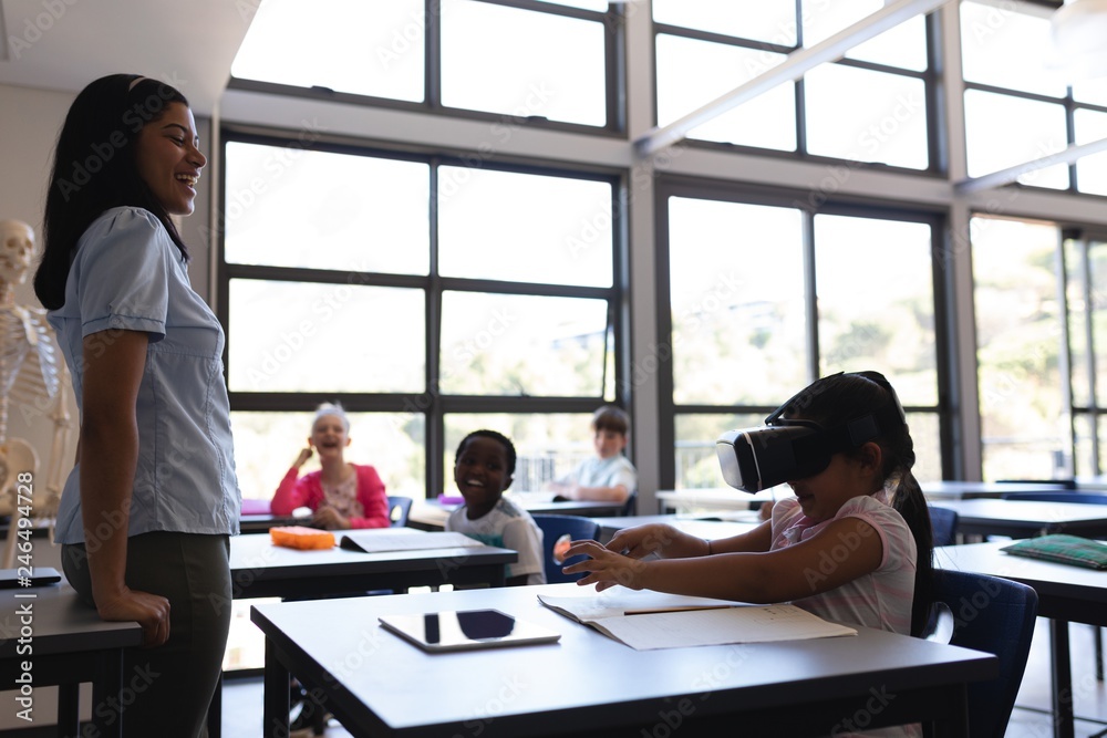 School girl using virtual reality headset at desk in classroom School girl using virtual reality headset at desk in classroom