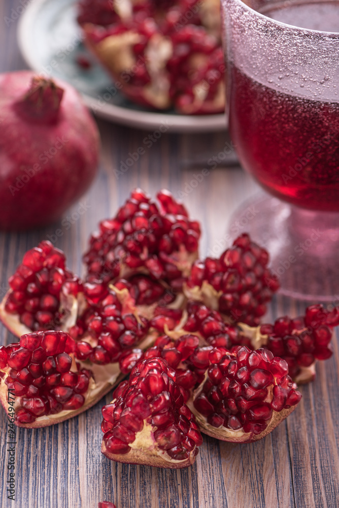 Pomegranate juice in a glass with fresh pomegranates around with scattered seeds on rustic wooden background 6 Pomegranate juice in a glass with fresh pomegranates around with scattered seeds on rustic wooden background 6