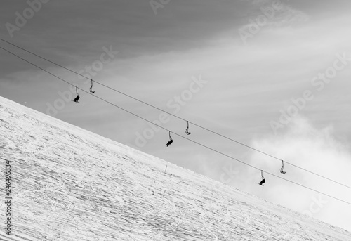 Snowy off-piste ski slope with traces from skis and snowboards and chair-lift