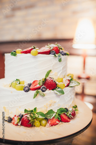 Three parts naked wedding cake with fruits and berries.