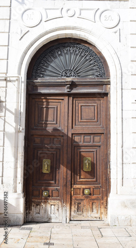 Puerta de madera clásica sobre muro blanco.