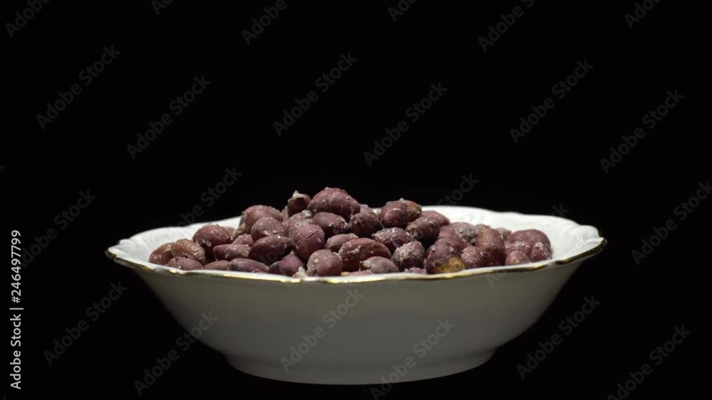 Raw unpeeled peanuts fried with salt. Rotation. Snack closeup. Peanuts in a bowl. Selective focus. black background. Studio shot. Healthy food concept. Raw unpeeled peanuts fried with salt. Rotation. Snack closeup. Peanuts in a bowl. Selective focus. black background. Studio shot. Healthy food concept.