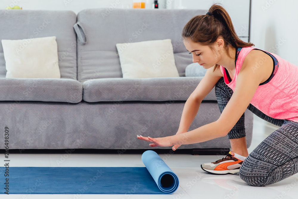 Young woman with yoga mat indoors, preparing for exercise, unrolling or rolling yoga mat Young woman with yoga mat indoors, preparing for exercise, unrolling or rolling yoga mat