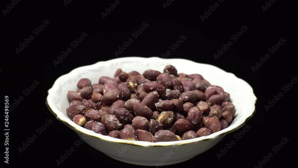 Raw unpeeled peanuts fried with salt. Rotation. Snack closeup. Peanuts in a bowl. Selective focus. black background. Studio shot. Healthy food concept. Raw unpeeled peanuts fried with salt. Rotation. Snack closeup. Peanuts in a bowl. Selective focus. black background. Studio shot. Healthy food concept.