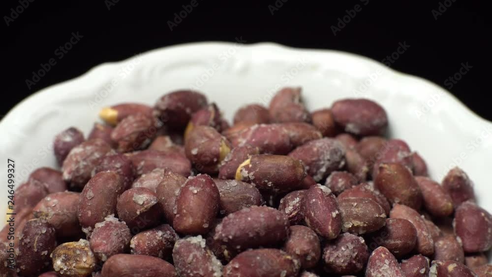 Raw unpeeled peanuts fried with salt. Rotation. Snack closeup. Peanuts in a bowl. Selective focus. black background. Studio shot. Healthy food concept. Raw unpeeled peanuts fried with salt. Rotation. Snack closeup. Peanuts in a bowl. Selective focus. black background. Studio shot. Healthy food concept.