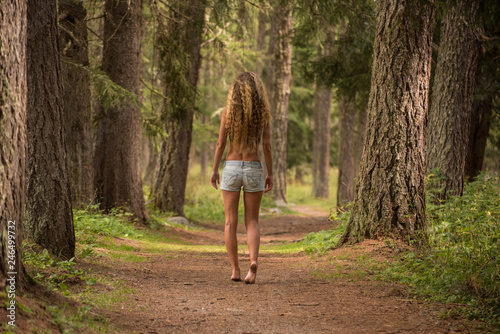 Ragazza cammina a piedi nudi nel bosco photo