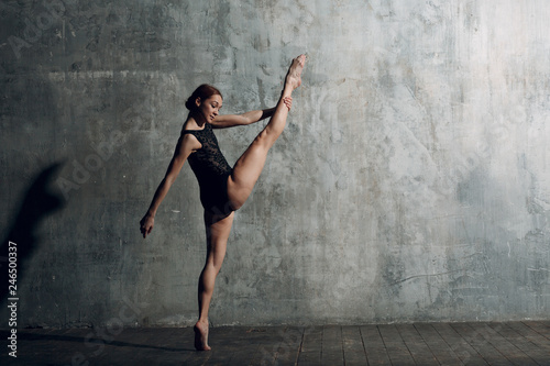 Ballerina stretching. Young beautiful woman ballet dancer, dressed in professional outfit, pointe shoes and black body.